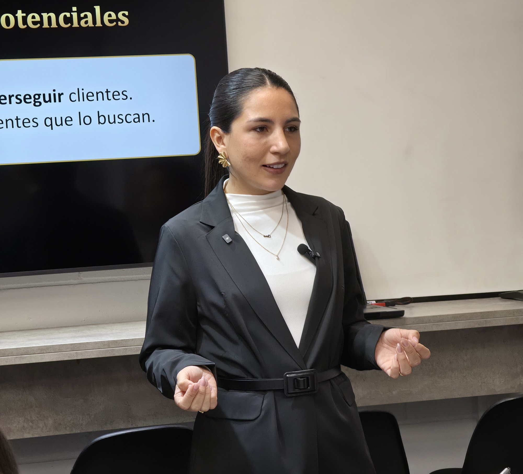 Clara Pérez en el escenario de su conferencia de marketing inmobiliario, frente a la pantalla que dice «tu mejor máquina de clientes potenciales»