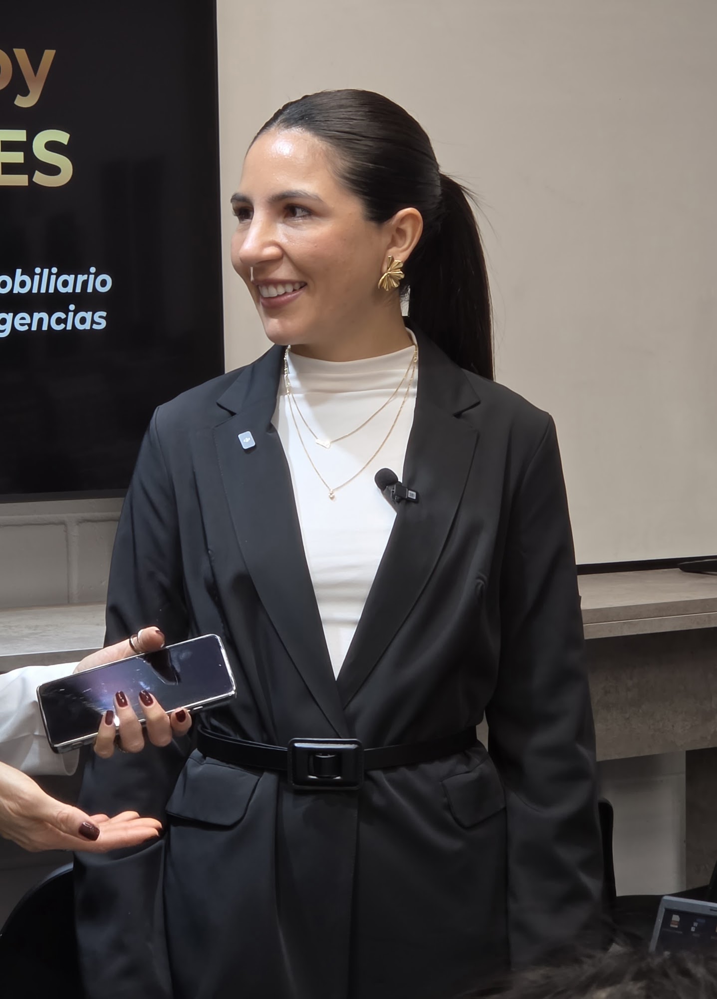 Clara Pérez sonriendo con el celular en la mano, durante su conferencia para Coldwell Banker Grupo Élite